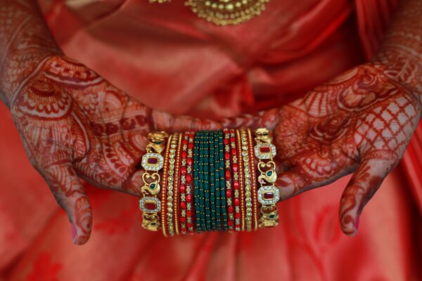 Close-up of henna-tattooed hands holding intricate Indian bangles, symbolizing tradition and celebration.