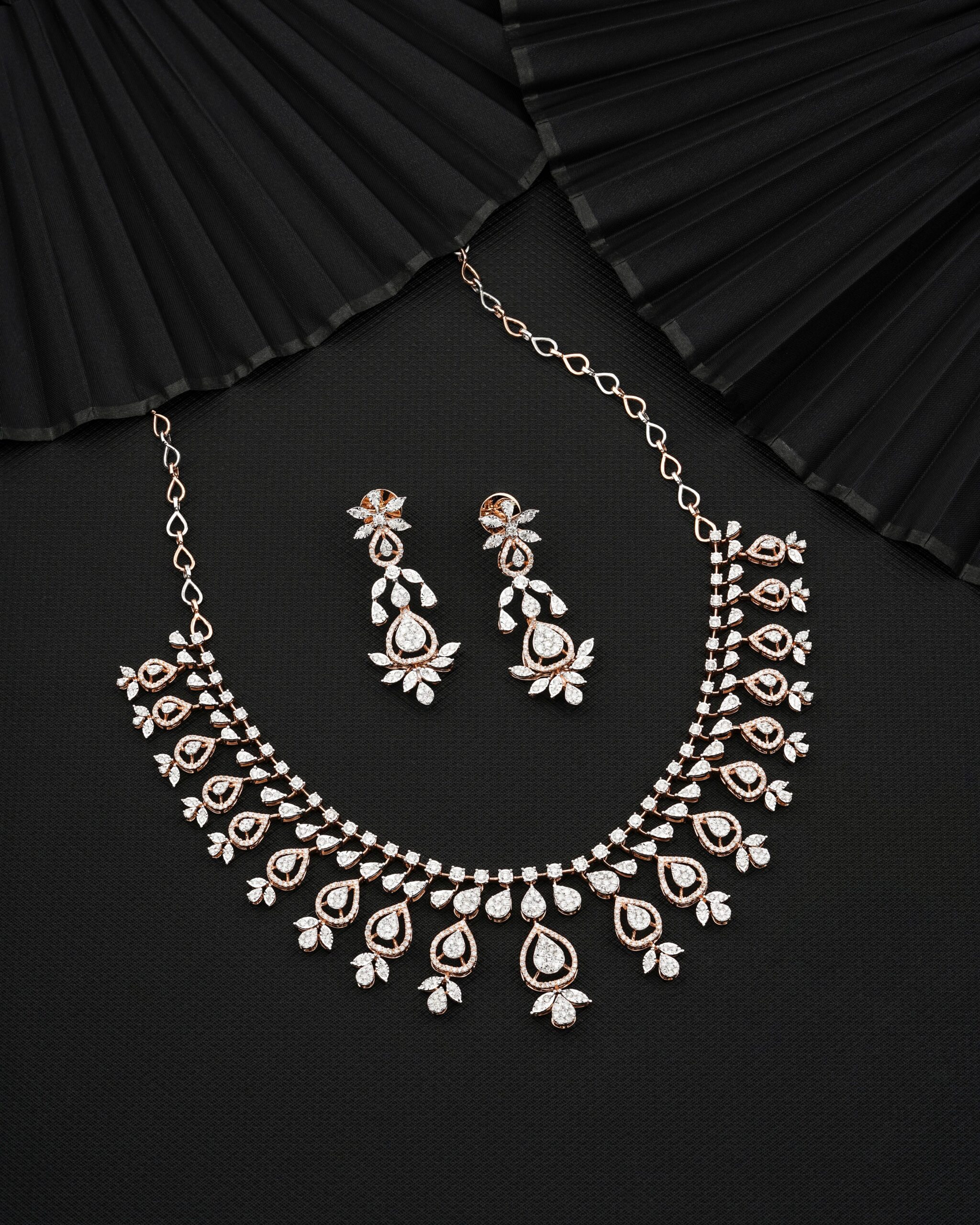 A beautiful diamond necklace and earrings set elegantly displayed on a dark fabric.