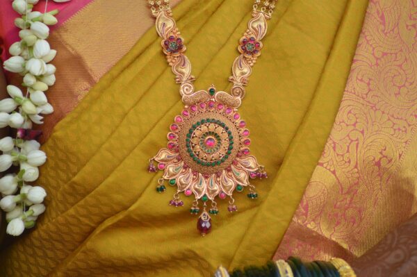 Intricate traditional gold necklace with gemstones on vibrant sari fabric.